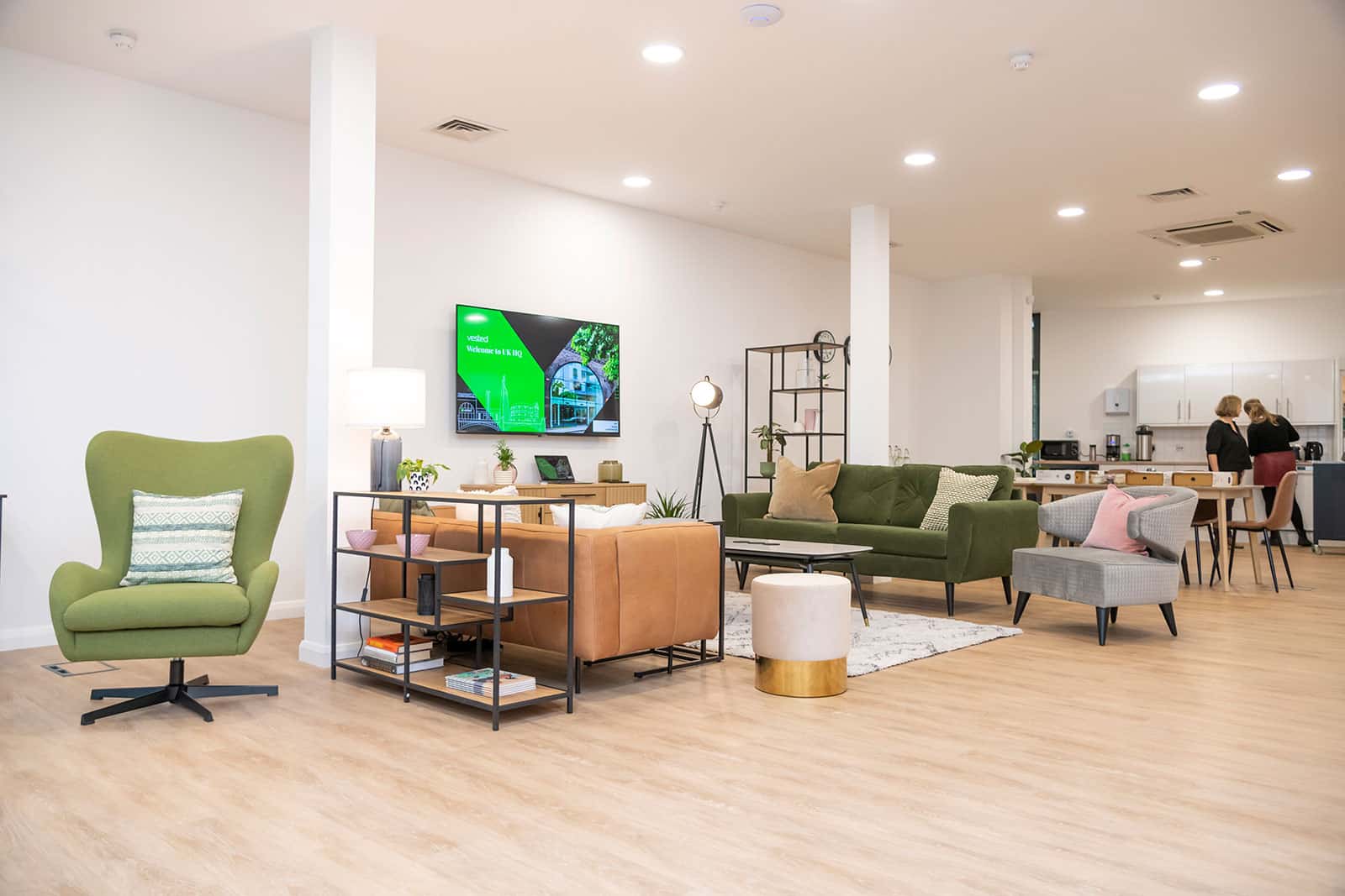 Interior of the London headquarters of Vested, with casual furniture in shades of green, tan, and grey.