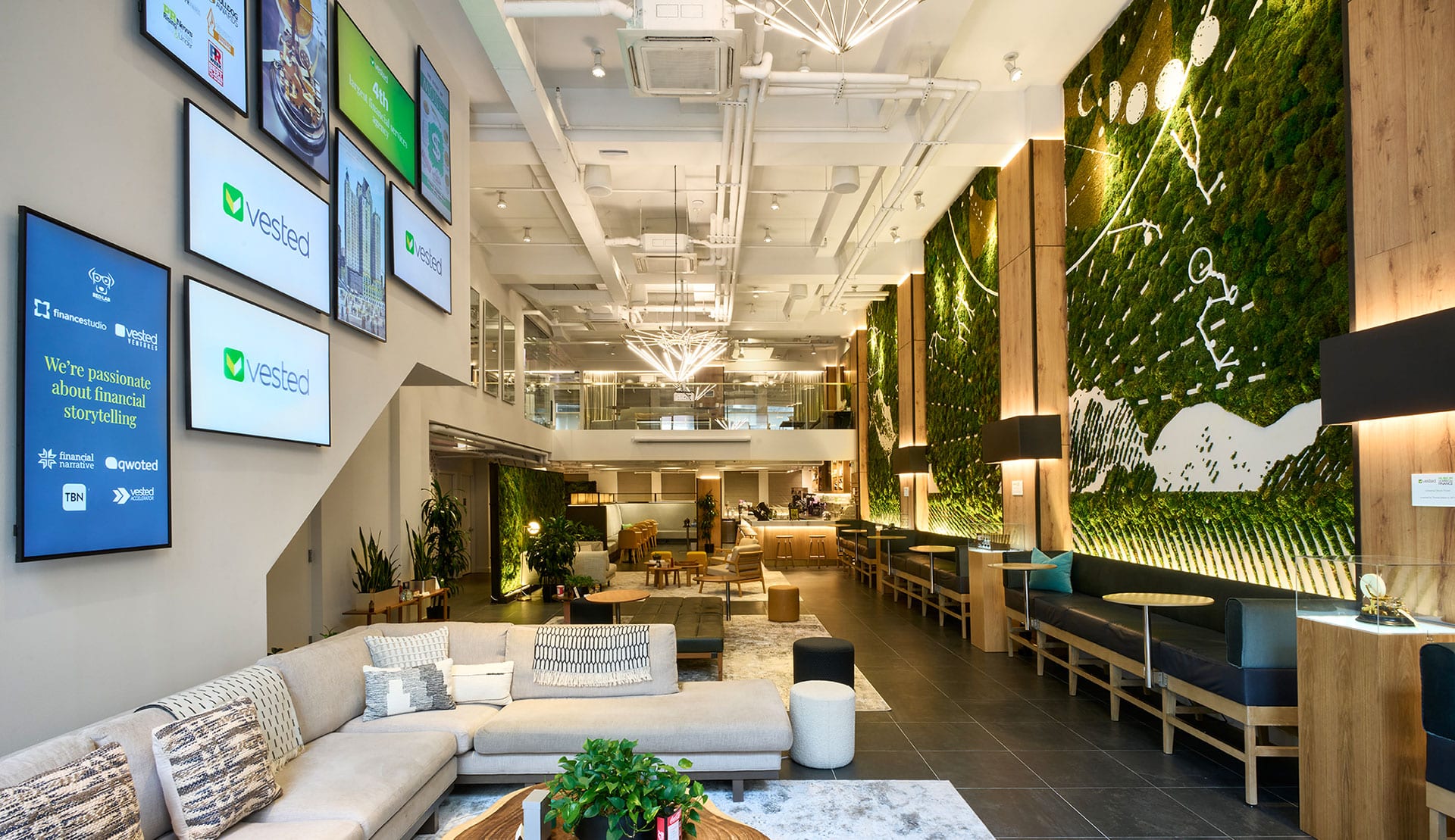 The interior of the NYC headquarters with oversized couches and lots of greenery, in a high ceiling loft-like modern space.